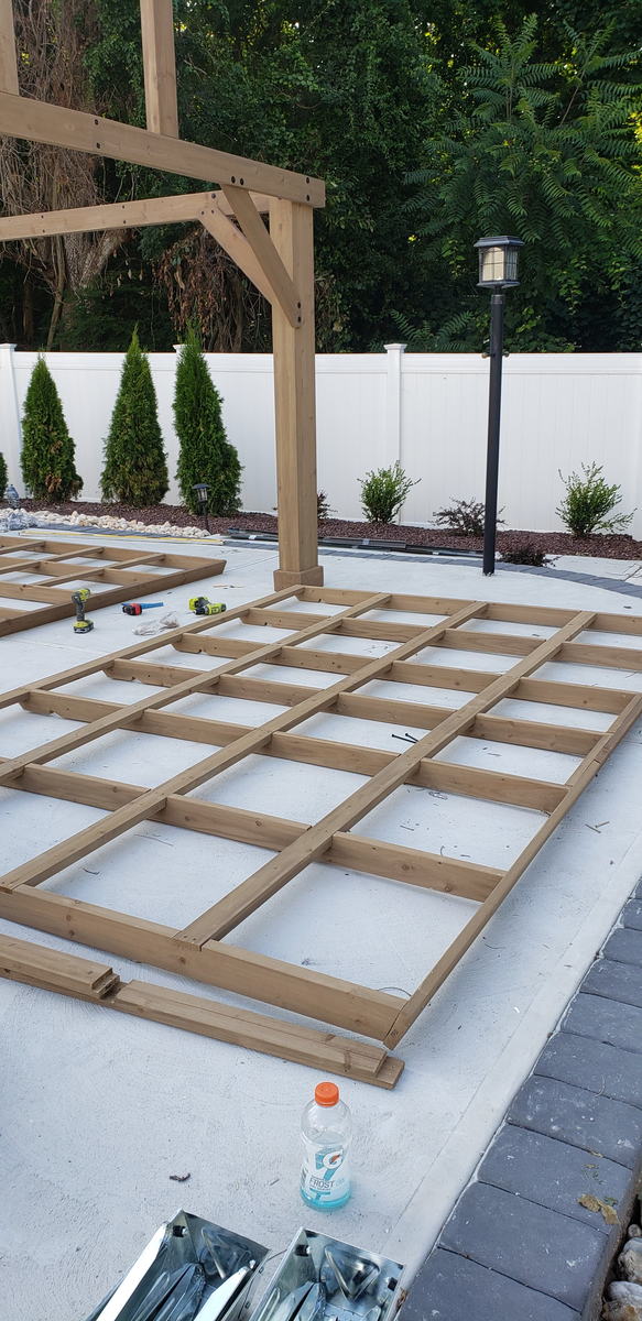 Pressure-treated deck framing laid out and squared on a concrete pool patio