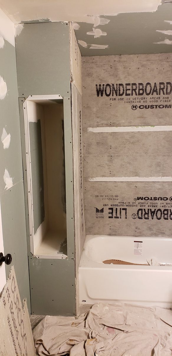 Tub alcove with the window wall closed up and boarded in cement board, a tall niche framed at one end and the new tub set