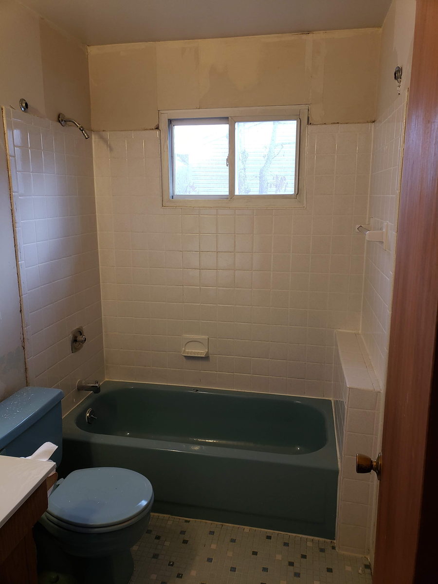 Dated bathroom with a blue tub and toilet and white square wall tile