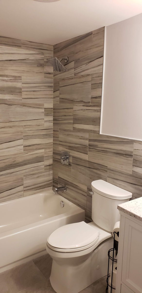 Large-format wood-look tile tub surround with chrome fixtures and a white tub