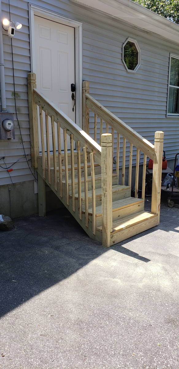 New pressure-treated entry stairs with turned balusters and a full handrail