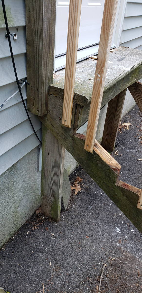 Rotted timber post cut away at the base above cracked asphalt