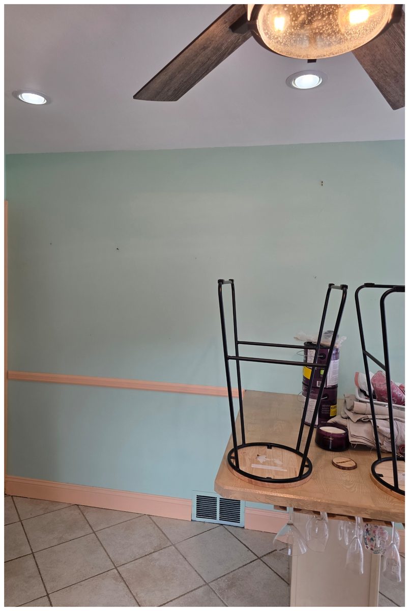 Dining nook with mint green walls and a peach chair rail and baseboard before repainting
