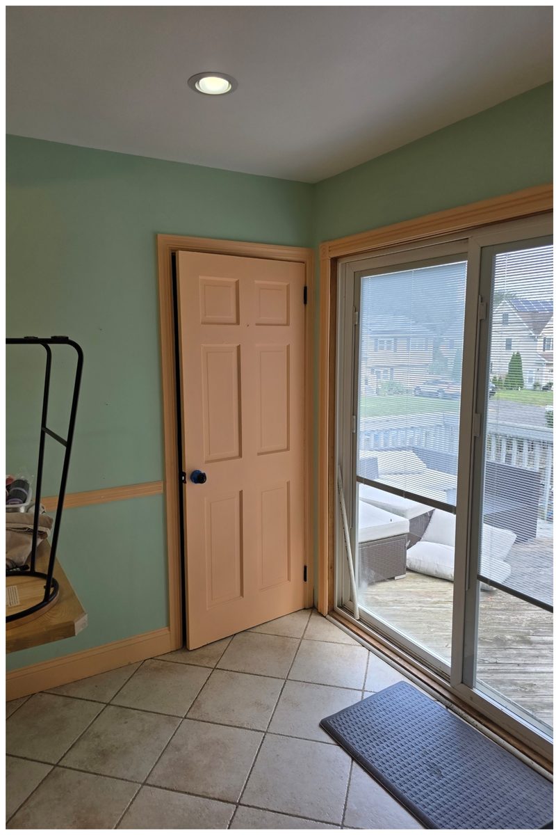 Corner of a dining nook with a peach six-panel door and casing beside a sliding glass door