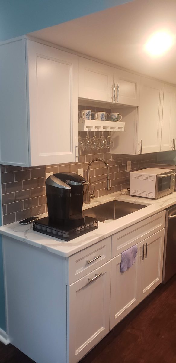 The same sink wall rebuilt in white shaker cabinets with a quartz counter, gray subway tile backsplash and a stainless undermount sink