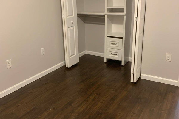 White closet shelving system with hanging rails and fixed shelves installed in a reach-in closet