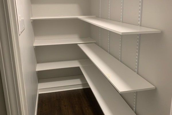 Custom white pantry shelving wrapping two walls with adjustable shelves