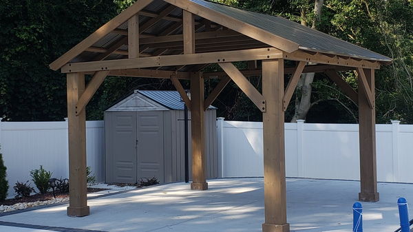 Finished timber-frame pavilion with a metal roof standing on a concrete pool patio