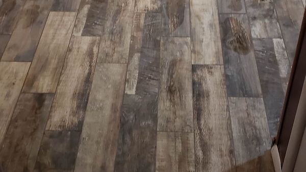 Multi-tone wood-look plank tile floor running through a living room and hallway