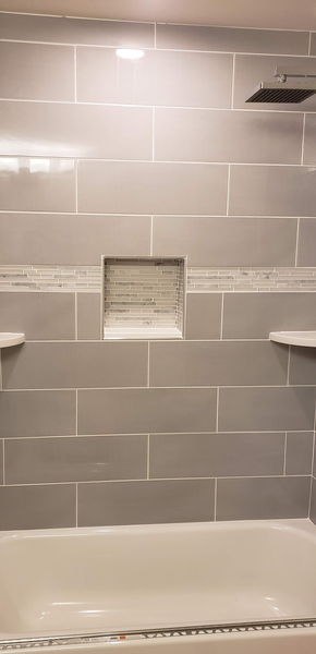 Gray tile tub surround with a recessed niche and a mosaic accent band