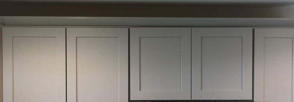 White shaker wall cabinets running to the ceiling with crown moulding