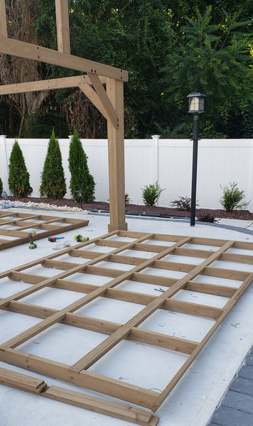 Pressure-treated deck framing squared up on a concrete patio before decking