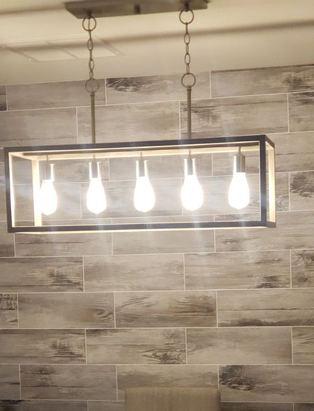 Wood-look tile accent wall lit by a five-bulb linear pendant