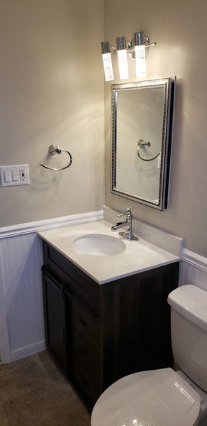 Powder room with a dark wood vanity, white top and beadboard wainscot