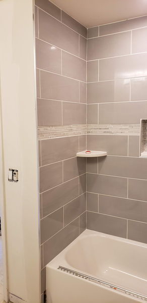 Gray tile shower with a recessed niche and a glass mosaic accent band