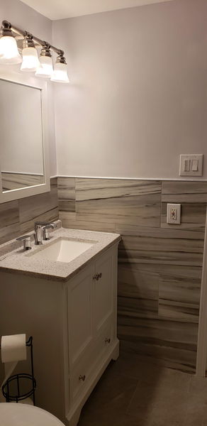 Wood-look tile wall running behind a white vanity and framed mirror