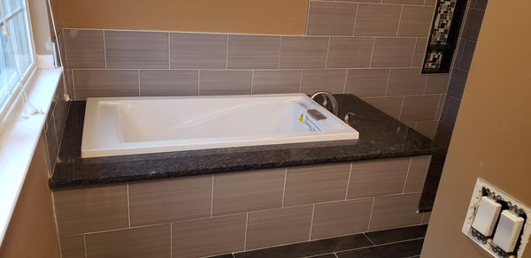 Tiled tub deck with a granite surround and a drop-in soaking tub