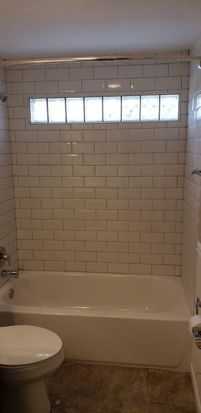 White subway tile tub surround with chrome fixtures and a curtain rod