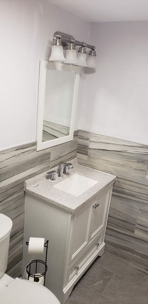 White vanity and mirror set against a wood-look tile wainscot