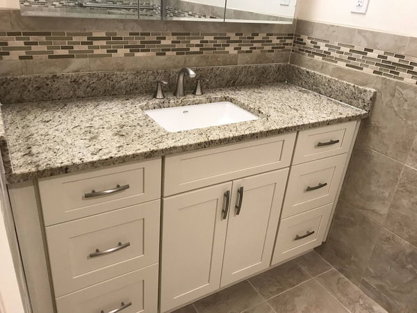 Bathroom vanity with a granite top, undermount sink and glass mosaic backsplash
