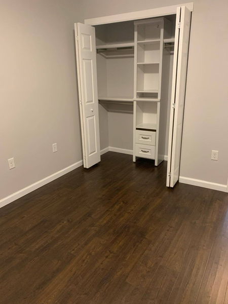 White closet shelving system with drawers, opened onto a dark hardwood floor