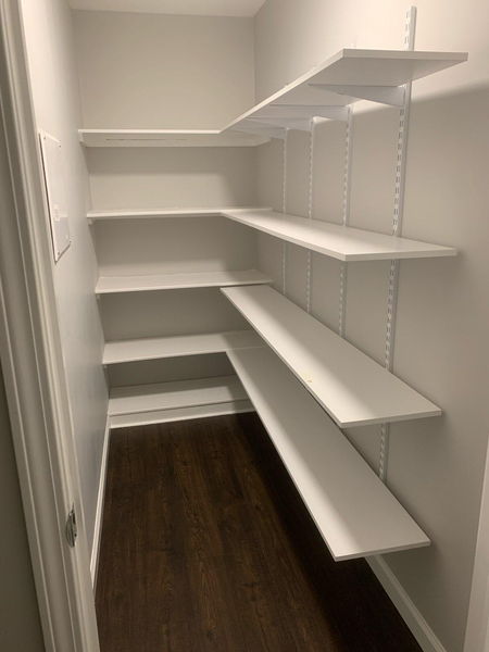 Custom white pantry shelving wrapping two walls from floor to ceiling