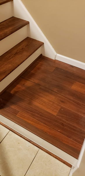 Stained hardwood stair treads meeting a matching hardwood landing floor