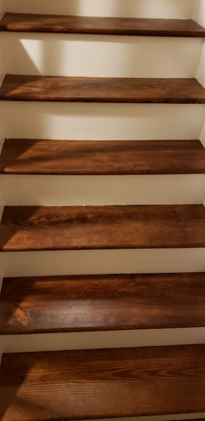 Close view of stained hardwood treads against crisp white risers