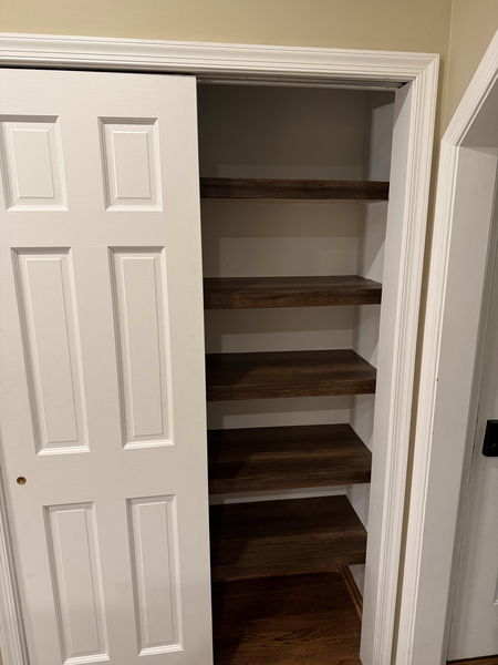 Solid wood closet shelving built in tiers inside a reach-in closet
