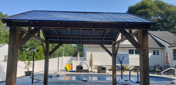 Cedar pavilion with a standing-seam metal roof over a pool patio