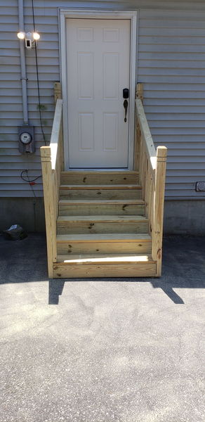 New pressure-treated entry stairs and railing leading to a side door