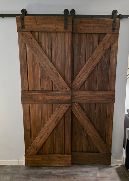 Pair of sliding barn doors with X bracing in a dark walnut stain, hung on a black top-mount track