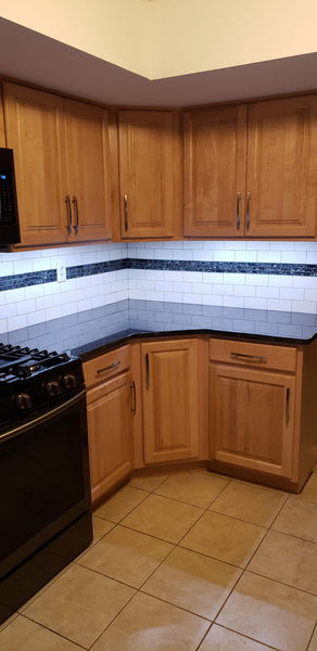 Subway tile backsplash turning a corner above dark granite counters