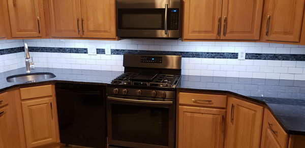 White subway tile backsplash with a dark glass mosaic accent band