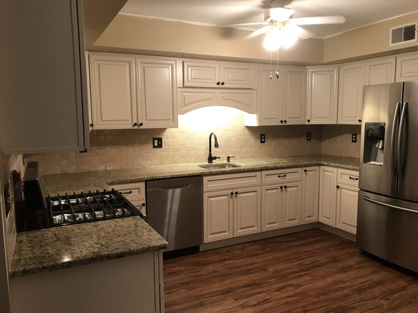 Cream kitchen cabinets with granite counters, tile backsplash and stainless appliances