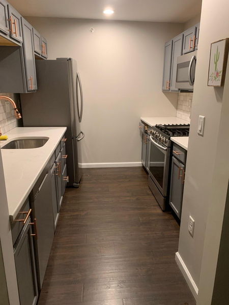 Galley kitchen with gray cabinets, quartz counters and copper hardware