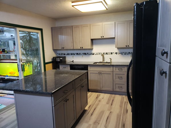 Granite-topped kitchen island above a light wood-look plank floor