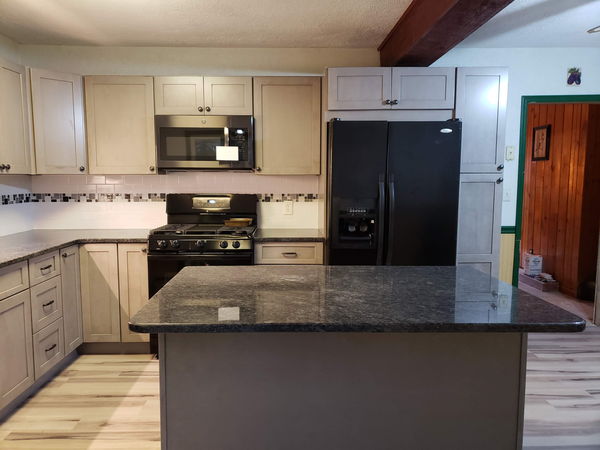 Gray shaker kitchen with a large granite island and a mosaic backsplash band