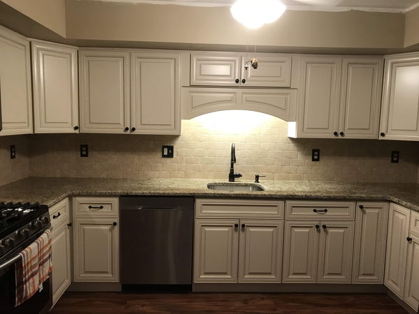 White kitchen cabinets with a stone tile backsplash and undermount sink