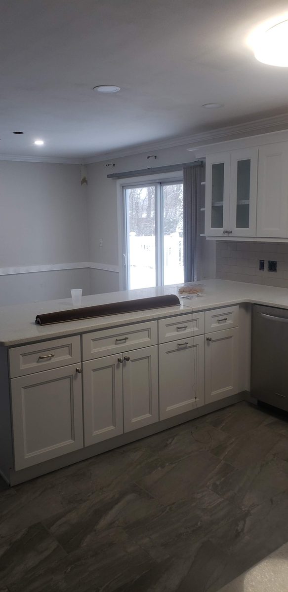 White shaker kitchen with a quartz peninsula, glass-front upper cabinets and a subway tile backsplash