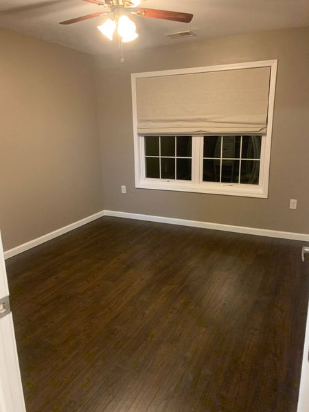 Dark hardwood flooring in an empty bedroom with a white-trimmed window
