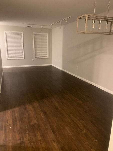 Dark hardwood flooring across an empty dining room below a linear pendant