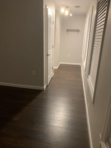 Dark hardwood flooring running the length of a hallway past white doors
