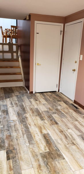 Wood-look plank tile floor meeting square white tile at an entry