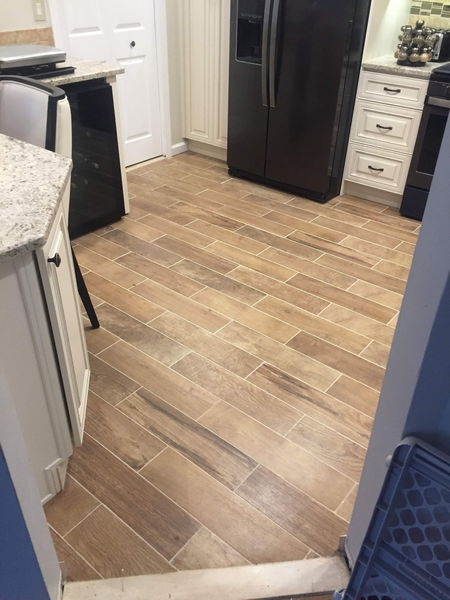 Wood-look floor tile running through a kitchen past dark appliances