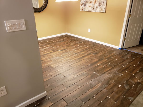 Wood-look floor tile meeting a painted wall and white baseboard